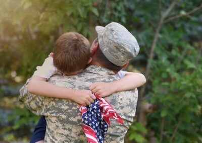 soldier carrying sa mall boy who is holding an American flag